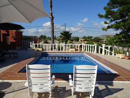 a swimming pool with two chairs and an umbrella at La Casa del Campo de La Matanza 