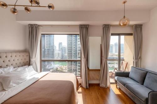 a bedroom with a bed and a couch and a large window at Beautiful stylish 1 bedroom by the JBR beach ! in Dubai