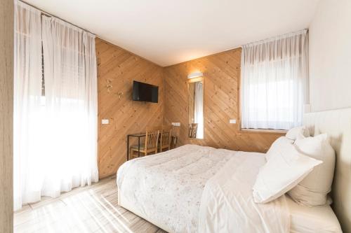 a bedroom with a white bed and a television at Hotel Vescovi in Asiago