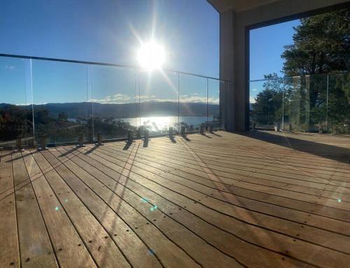 a room with a view of the sun on a glass wall at Jindabyne house 1, Modern 1 bedroom home, alpine views & fireplace in Jindabyne