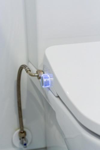 a water hose hooked up to a toilet in a bathroom at Serenity Getaway in Christchurch