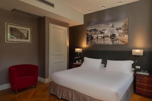 a bedroom with a white bed and a red chair at Hotel Principe Torlonia in Rome