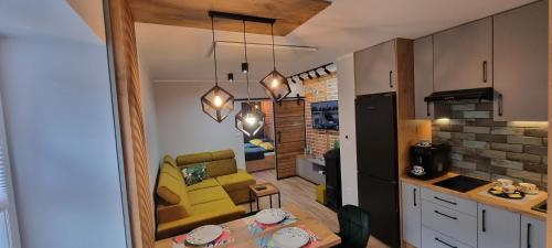 a kitchen and living room with a table and a yellow chair at Apartament LuxLoft2 in Piechowice