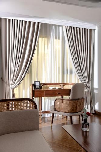 a living room with chairs and a desk and a window at La Siesta Classic Hang Thung in Hanoi