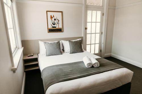 um quarto com uma cama grande com duas almofadas em The Imperial Hotel em Murwillumbah