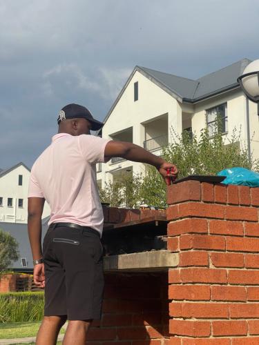 a man is leaning against a brick wall at Idesel Apartment in Edendale