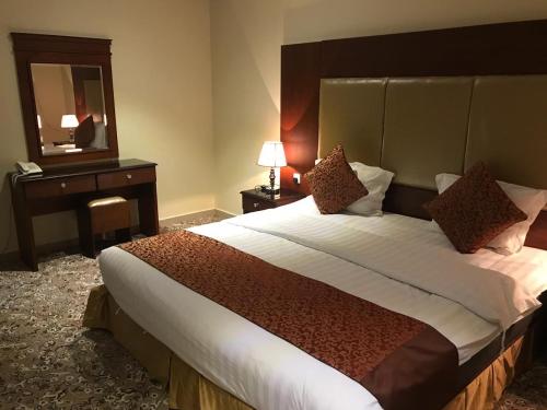 una camera d'albergo con un grande letto e uno specchio di داركم 2 للشقق المخدومة a Buraydah