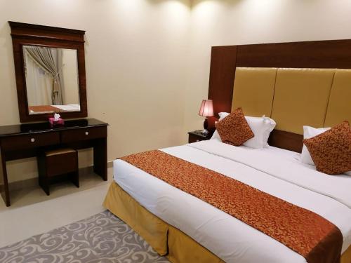 Cette chambre comprend un grand lit et un miroir. dans l'établissement داركم 2 للشقق المخدومة, à Buraydah