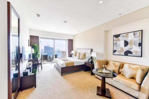 Address Marina Mall Suites "Full Marina Views & Balcony " في دبي: غرفه فندقيه بسرير واريكه