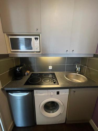 a small kitchen with a microwave and a washing machine at Dream Dwell Paris - Paris Expo Porte Versailles beautiful apartment with balcony in Issy-les-Moulineaux