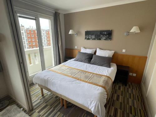 une chambre avec un grand lit avec une grande fenêtre dans l'établissement Dream Dwell Paris - Paris Expo Porte Versailles beautiful apartment with balcony, à Issy-les-Moulineaux