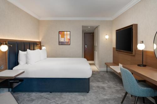 a hotel room with a large bed and a desk at Hilton London Metropole in London