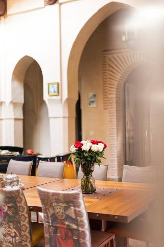 a wooden table with a vase of flowers on it at Villa Serena Marrakech - Maison d'hôtes in Marrakech