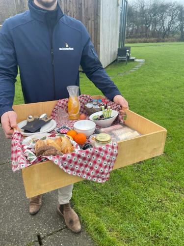 a man holding a box filled with food at Houseboats Pean-buiten Weidum in Weidum