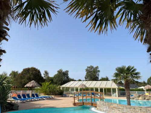 un complejo con piscina, sillas y palmeras en Camping de la Plage de Cleut-Rouz, en Fouesnant
