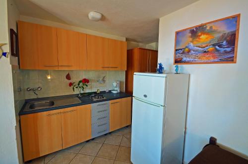 a kitchen with wooden cabinets and a white refrigerator at Villa Goga in Martinšćica