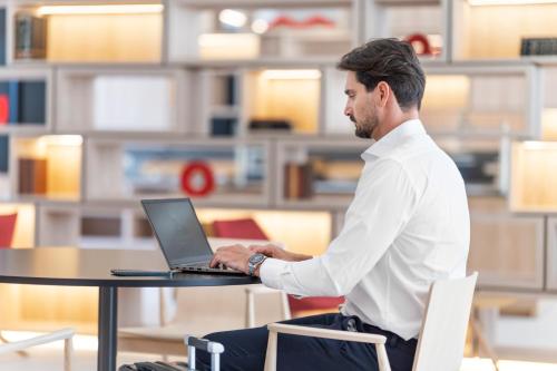 a man sitting at a table using a laptop computer at Moov Hotel Lisboa Oriente in Lisbon