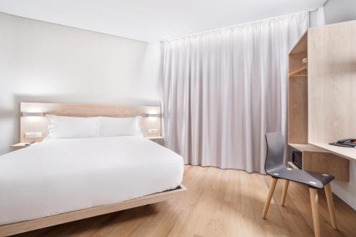 a hotel room with a bed and a chair at Moov Hotel Lisboa Oriente in Lisbon