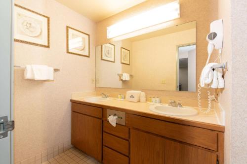 baño con lavabo y espejo grande en Days Inn by Wyndham Coeur d'Alene, en Coeur d'Alene