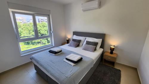 1 dormitorio con 1 cama con 2 almohadas y ventana en The Sands LUXE Pool Aparthotel 3, en Novalja