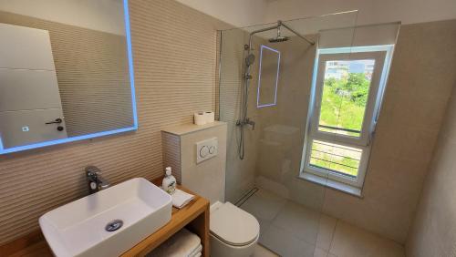 baño con lavabo y aseo y ventana en The Sands LUXE Pool Aparthotel 3, en Novalja