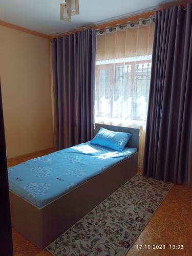 a bedroom with a bed and a window with purple curtains at INJIR Hostel in Dushanbe