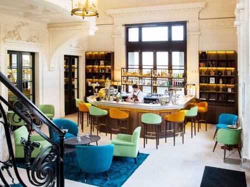 a bar with colorful chairs and a man sitting at a counter at Novotel Domaine de Maffliers - L'Isle-Adam in Maffliers