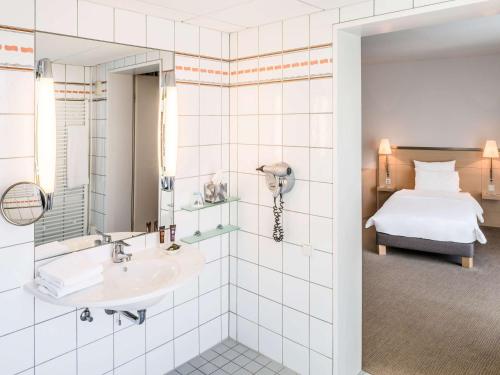 a bathroom with a sink and a bed in a room at Novotel Berlin Mitte in Berlin