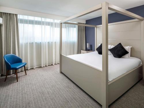 a bedroom with a canopy bed and a blue chair at Mercure Manchester Piccadilly Hotel in Manchester