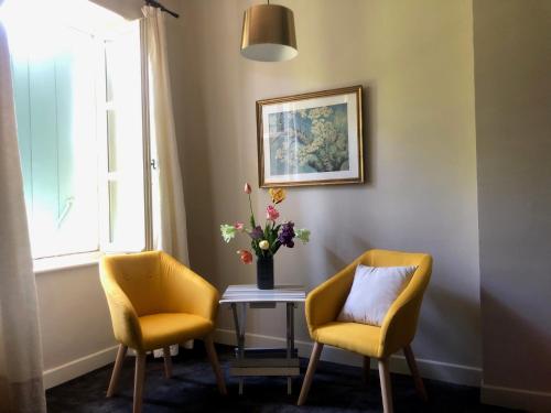 two chairs and a table with a vase of flowers at La Cerisaie - Chambres d'hôtes & gites in Riols