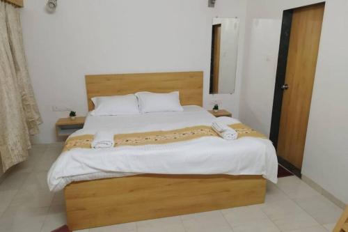 a bedroom with a large wooden bed with white sheets at Lonavala Villa in Lonavala