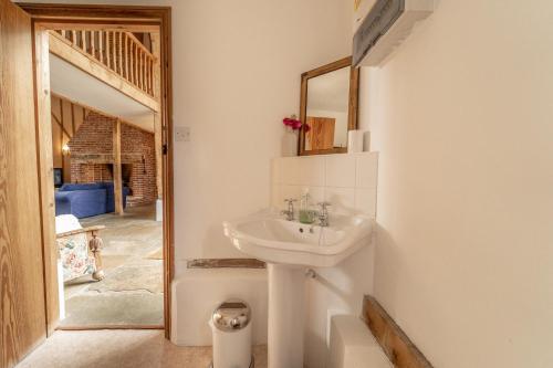 W łazience znajduje się umywalka i lustro. w obiekcie Manor Farm Barn w mieście Eye