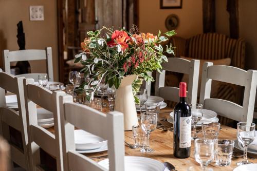 a table with a vase of flowers and a bottle of wine at Manor Farm Barn in Eye