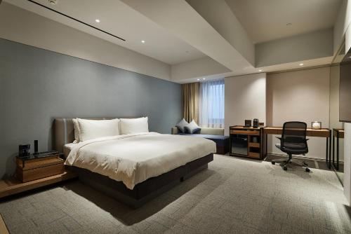 K Hotel Taipei Nanjing في تايبيه: غرفة نوم بسرير ومكتب وكرسي