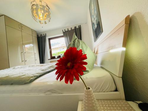 a red flower in a vase on a table in a bedroom at Ferienwohnung Pupeter in Arzl im Pitztal