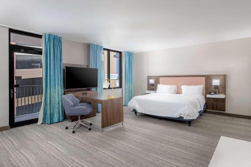 a hotel room with a bed and a desk and a tv at Hampton Inn & Suites - Orange Beach in Orange Beach