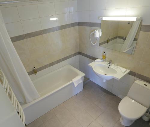 a bathroom with a tub and a toilet and a sink at Aurora Hotel Klaipeda in Klaipėda