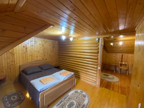a small room with a bed in a wooden cabin at Pid Playem in Volovets