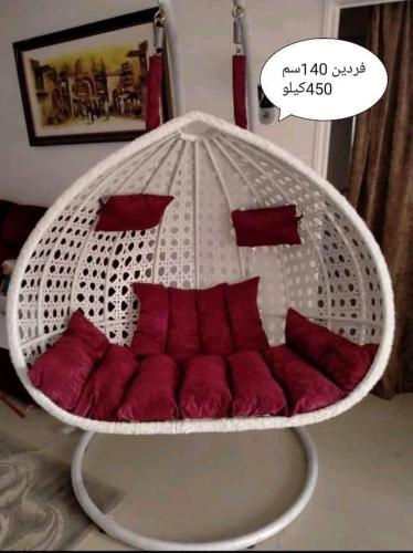 a hanging bed with red pillows in a room at شقه بحديقه رائعه in Cairo