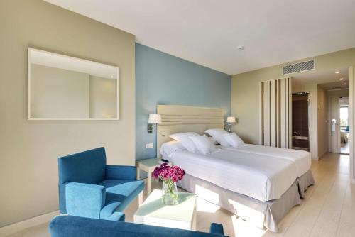 a bedroom with a large bed and a blue chair at Barceló Costa Ballena Golf & Spa in Costa Ballena