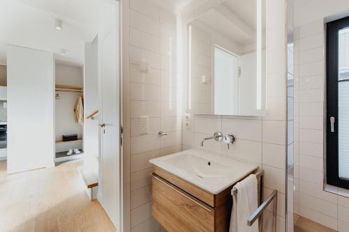 a white bathroom with a sink and a mirror at SandKorn 1 und 2 in Pruchten