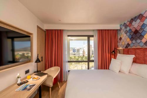 a hotel room with a bed and a desk and a window at Barceló Fès Medina in Fès