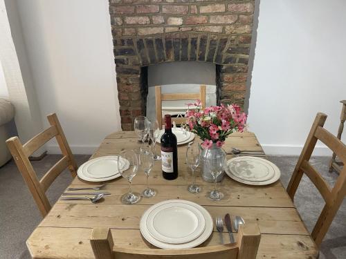 une table en bois avec une bouteille de vin et des verres dans l'établissement Poplar Cottage Farnborough Kent, à Orpington