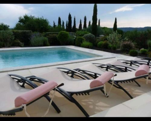 un groupe de chaises assises à côté d'une piscine dans l'établissement Villa les Deux Cypres, à Saint-Laurent-de-la-Cabrerisse