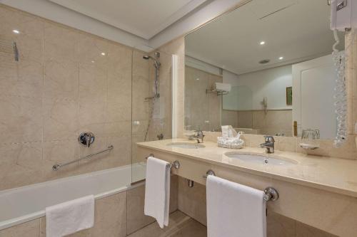 a bathroom with a sink and a tub and a mirror at Barceló Jerez Montecastillo & Convention Center in Jerez de la Frontera