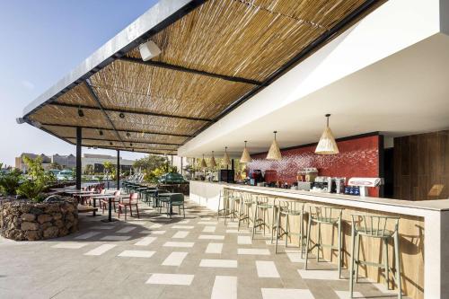 an outdoor patio with a bar with chairs and tables at Barceló Lanzarote Active Resort in Costa Teguise