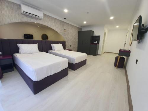 a hotel room with two beds and a television at Karikatür Bi Hotel in Alanya