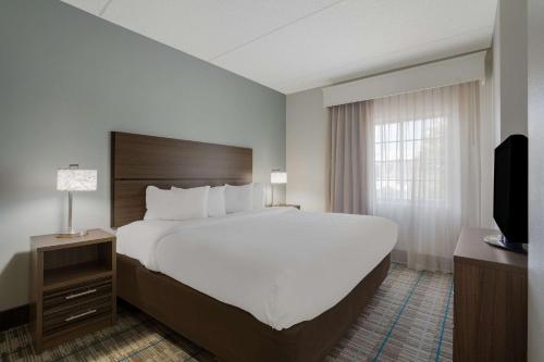 um quarto de hotel com uma cama grande e uma televisão em MainStay Suites Wilmington em Wilmington
