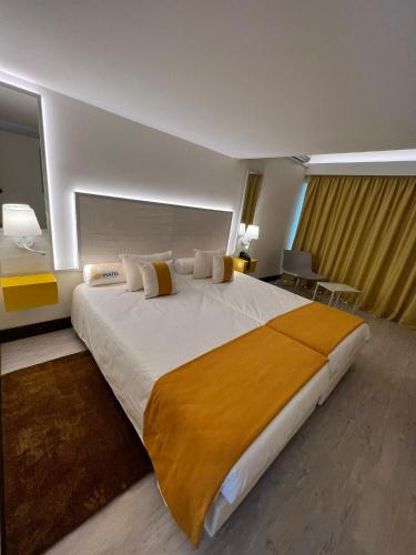 um quarto com uma cama grande e um cobertor amarelo em INATEL Oeiras em Oeiras