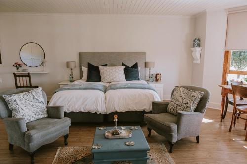 a bedroom with a bed with two chairs and a table at Thyme Out Weltevreden Farm in Curryʼs Post